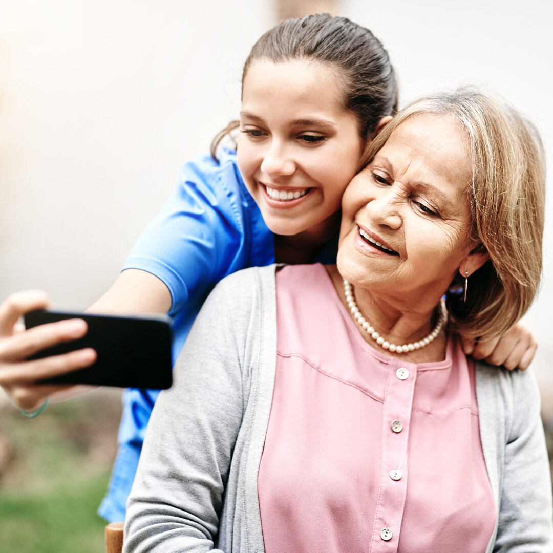 Cropped shot of a caregiver taking a selfie with a senior patient outside.